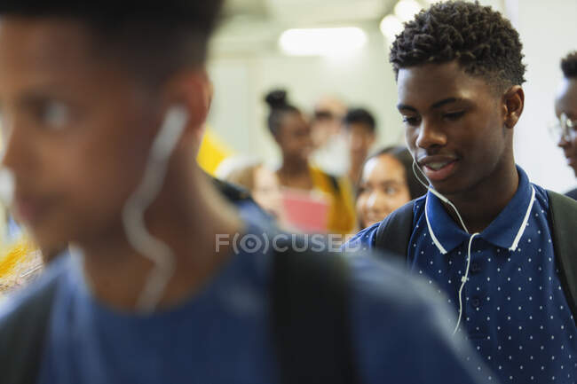Estudiante de secundaria con auriculares en el pasillo - foto de stock