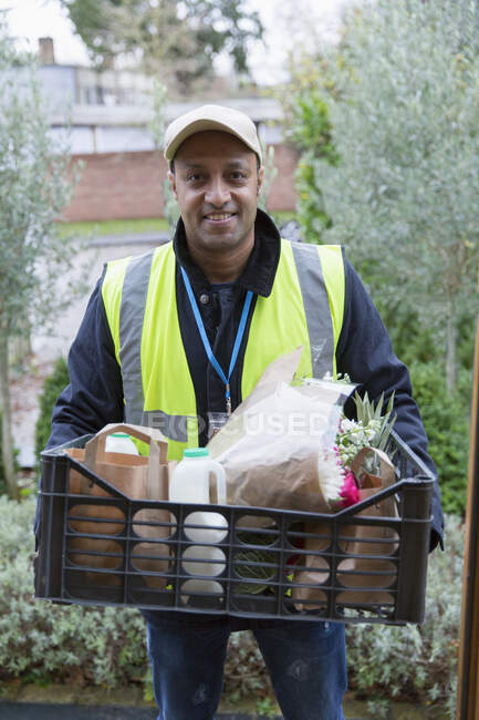 Portrait confident, friendly grocery deliveryman at front stoop — Stock Photo