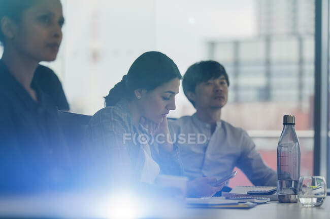 Empresária usando telefone inteligente na reunião da sala de conferências — Fotografia de Stock