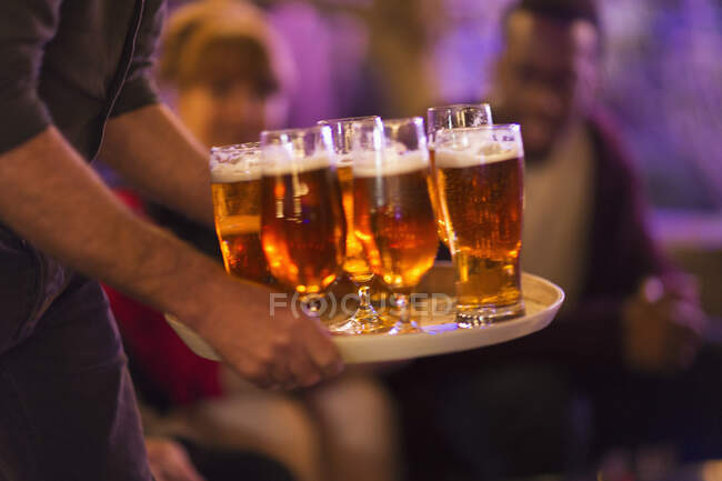 Man serving tray of beers to friends — Stock Photo