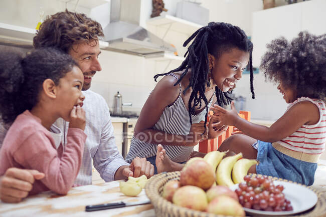 Молода сім'я їсть фрукти на столі — стокове фото