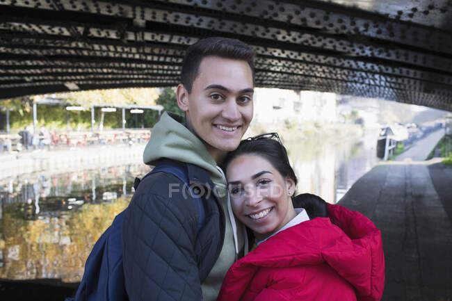 Portrait happy young couple hugging along canal — Stock Photo