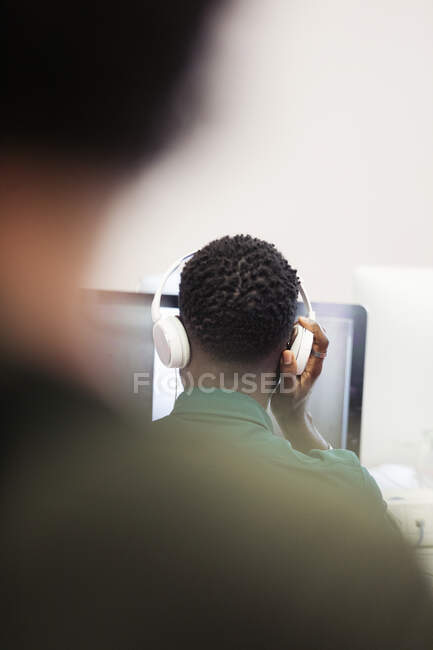 Estudiante universitario de la comunidad masculina madura con auriculares en la computadora - foto de stock