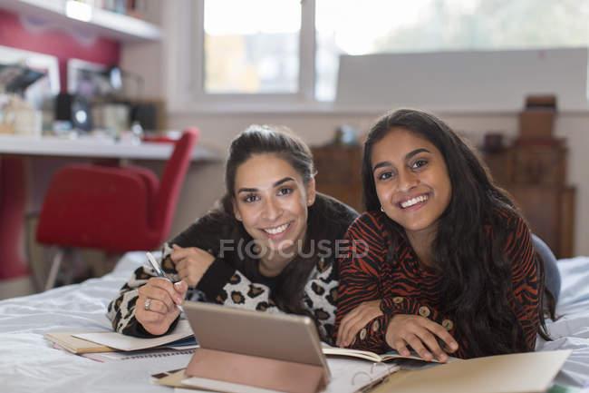 Portrait smiling confident teenage girl friends studying on bed — Stock Photo