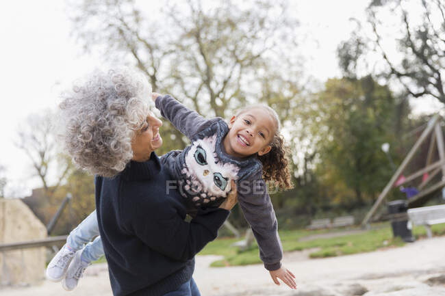 Ritratto giocoso nonna sollevamento nipote al parco giochi — Foto stock