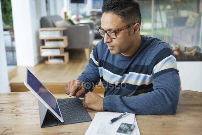 Focused man paying bills at digital tablet — Stock Photo