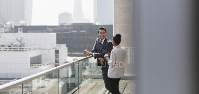Uomini d'affari che parlano sul balcone soleggiato e urbano — Foto stock
