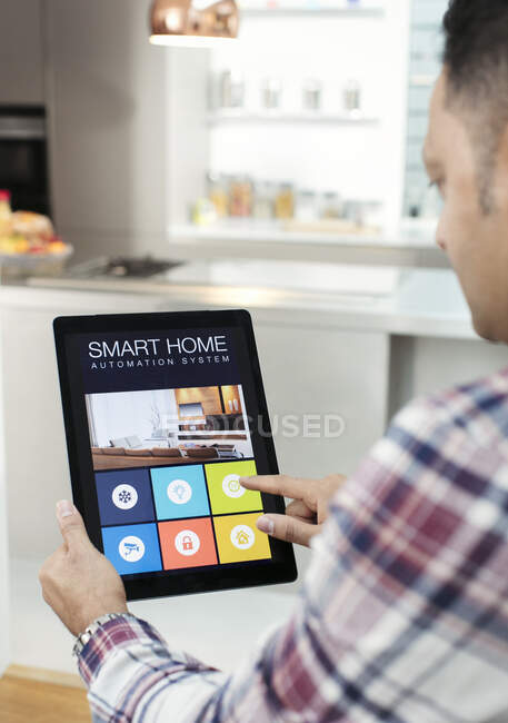 Homem que controla o sistema de navegação em casa inteligente a partir de tablet digital na cozinha — Fotografia de Stock