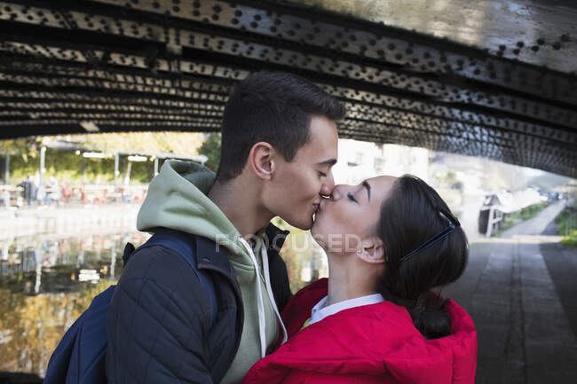 Любящая молодая пара целуется под мостом — стоковое фото