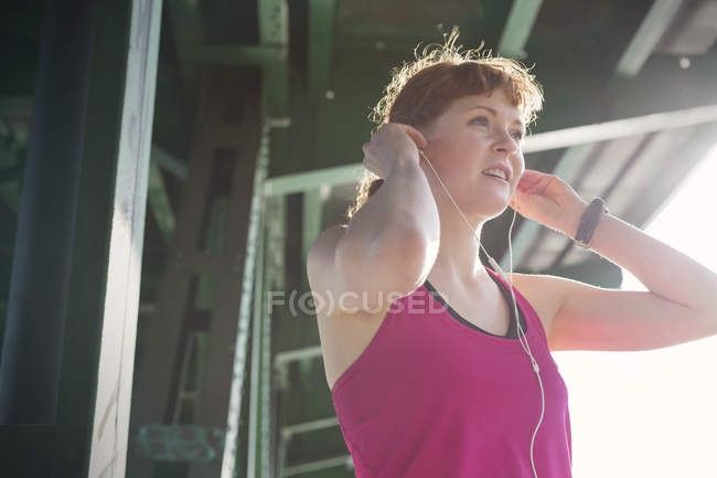 Corredor feminino ajustando fones de ouvido — Fotografia de Stock