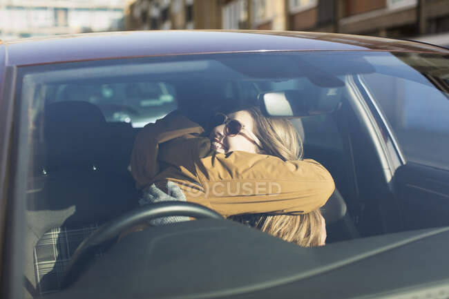 Casal afetuoso abraço em carro ensolarado — Fotografia de Stock