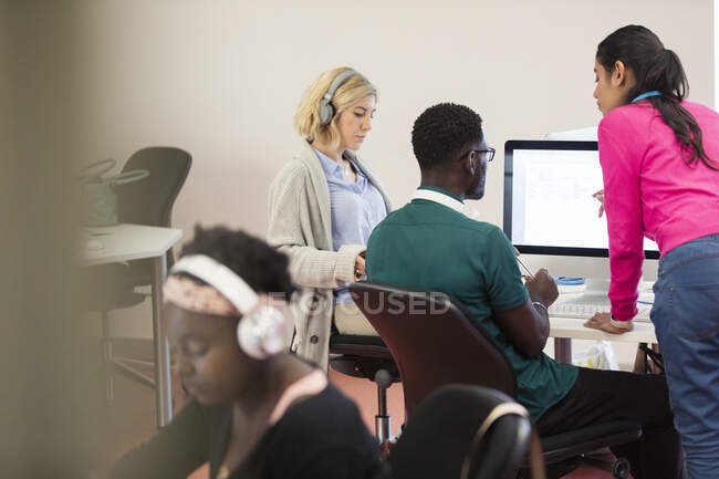 Преподаватель общественного колледжа помогает студентам за компьютерами в компьютерной лаборатории — стоковое фото