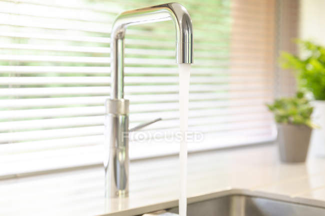 Chiudi l'acqua che scorre dal rubinetto della cucina in acciaio inossidabile — Foto stock