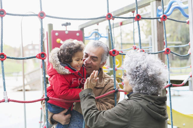 Grands-parents jouant avec petit-fils à l'aire de jeux — Photo de stock