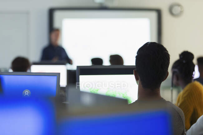 Étudiants du premier cycle du secondaire utilisant des ordinateurs, écoutant le professeur en classe — Photo de stock