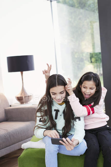 Irmãs brincalhões tirando selfie com telefone inteligente na sala de estar — Fotografia de Stock