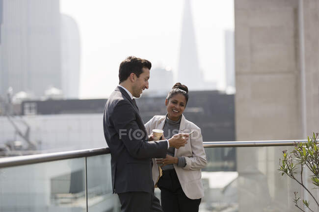 Uomini d'affari che parlano sul balcone soleggiato e urbano — Foto stock