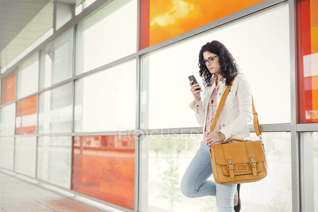 Молода жінка використовує смартфон на вокзалі — стокове фото