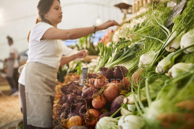 Mujer trabajando, organizando productos en el mercado de agricultores - foto de stock