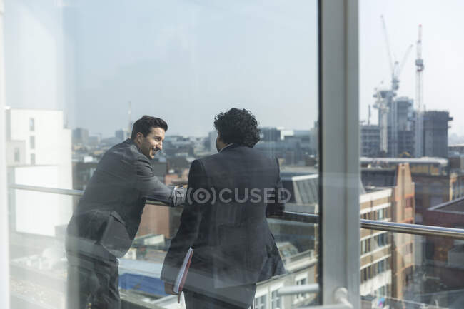 Des hommes d'affaires parlent sur un balcon ensoleillé et urbain — Photo de stock