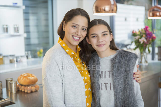 Retrato feliz madre e hija abrazándose en la cocina - foto de stock
