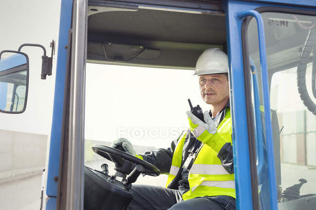 Dock worker using walkie-talkie and operating crane at shipyard — Stock Photo