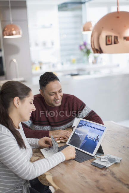 Happy couple planning vacation at digital tablet at dining table — Stock Photo