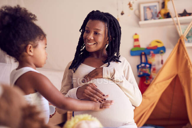 Cute toddler daughter touching mothers pregnant belly — Stock Photo