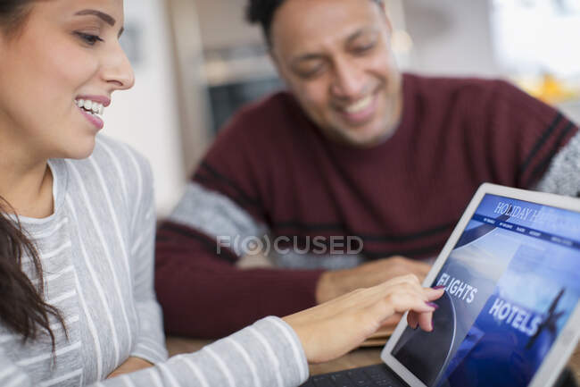 Felice coppia pianificazione vacanza al tablet digitale — Foto stock