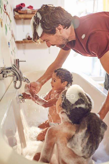 Батько дає маленьким донькам бульбашкову ванну — стокове фото
