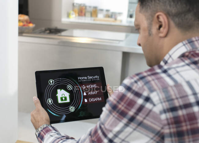 Man setting smart home security alarm from digital tablet in kitchen — Stock Photo