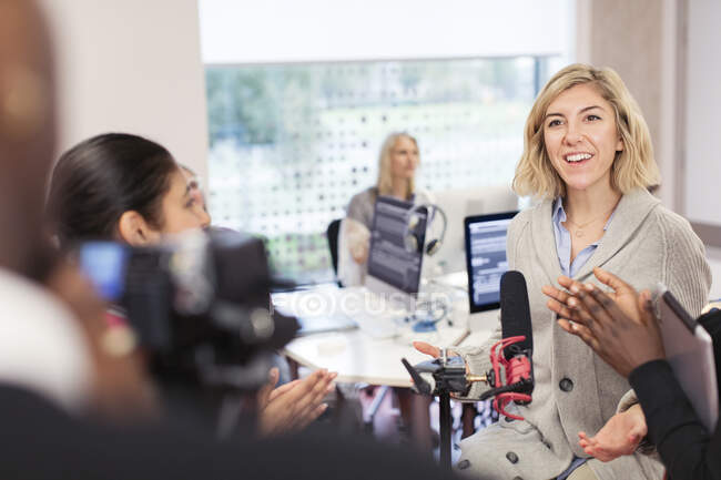 Classmates clapping for woman at microphone in journalism class — Stock Photo