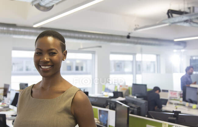 Портрет улыбается, уверенная деловая женщина в офисе открытого плана — стоковое фото