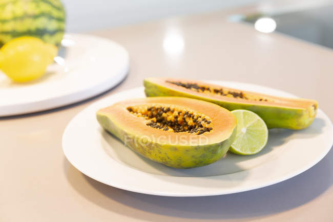 Frisch geschnittene Papaya mit Limette auf Teller — Stockfoto