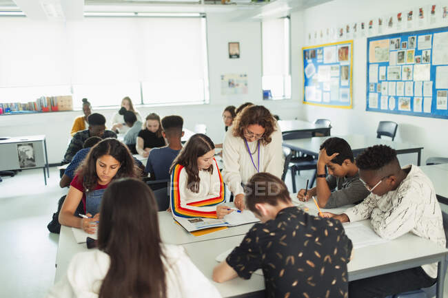 Professora do ensino médio ajudando alunos a estudar em sala de aula — Fotografia de Stock