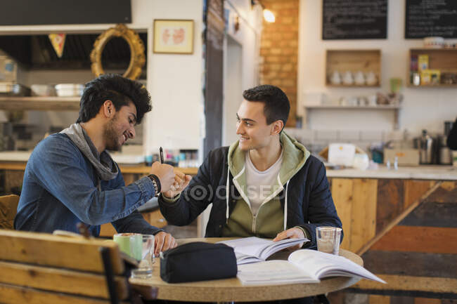 Young male college students studying, fist bumping in cafe — Stock Photo