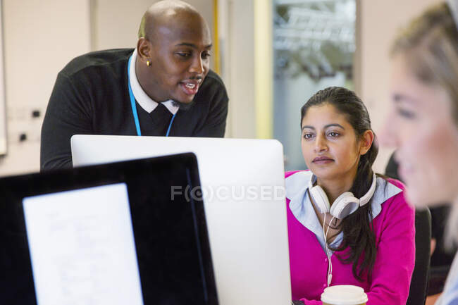 Instrutor universitário comunitário ajudando estudante em computador em sala de aula — Fotografia de Stock