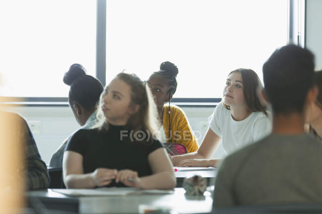 Estudiantes de secundaria atentos escuchando en el aula - foto de stock
