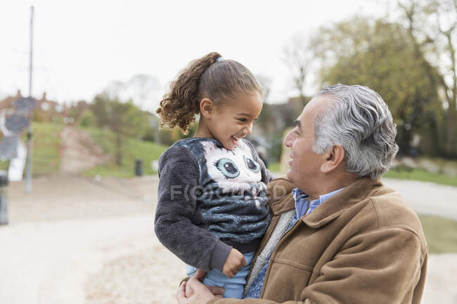 Усміхнений дідусь тримає онуку в парку — стокове фото