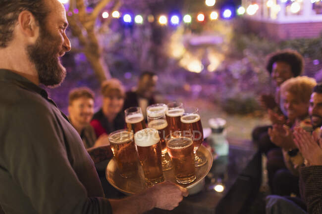 Homem que serve bandeja de cervejas para amigos na festa do jardim — Fotografia de Stock
