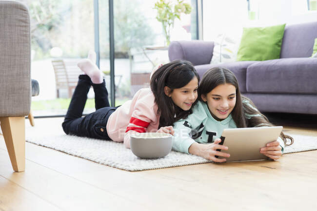 Дівчата дивляться фільм з цифровим планшетом на підлозі вітальні — стокове фото