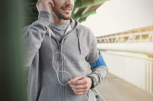 Corredor masculino escuchando música con auriculares y reproductor de mp3 - foto de stock