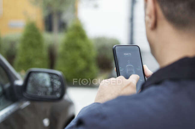 Uomo impostazione allarme auto da smart phone nel vialetto — Foto stock