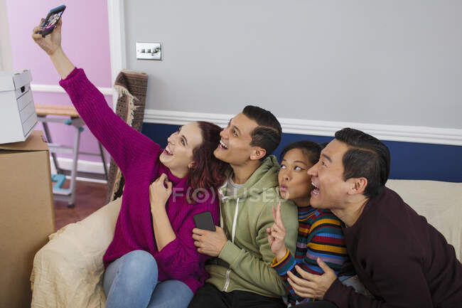 Playful friends taking a break from moving, taking a selfie with smart phone — Stock Photo