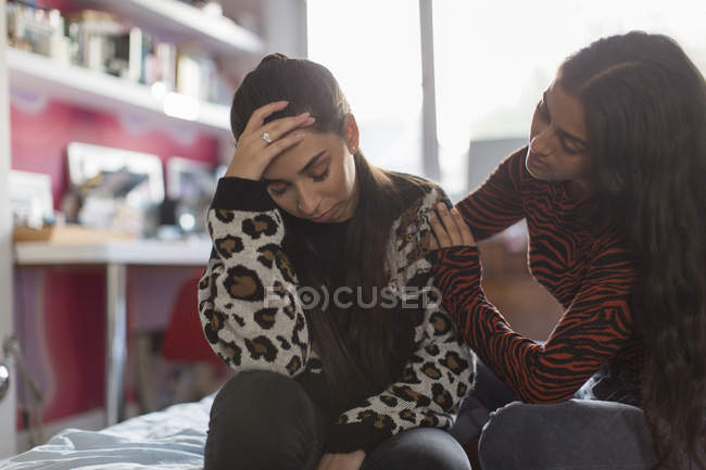 Дівчина-підліток заспокоює засмученого друга на ліжку — стокове фото