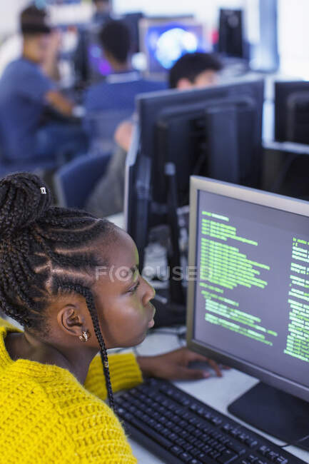 Focalisé junior lycéenne étudiant en utilisant l'ordinateur dans le laboratoire informatique — Photo de stock