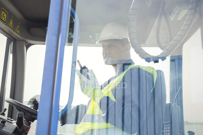 Dock worker with walkie-talkie operating forklift — Stock Photo