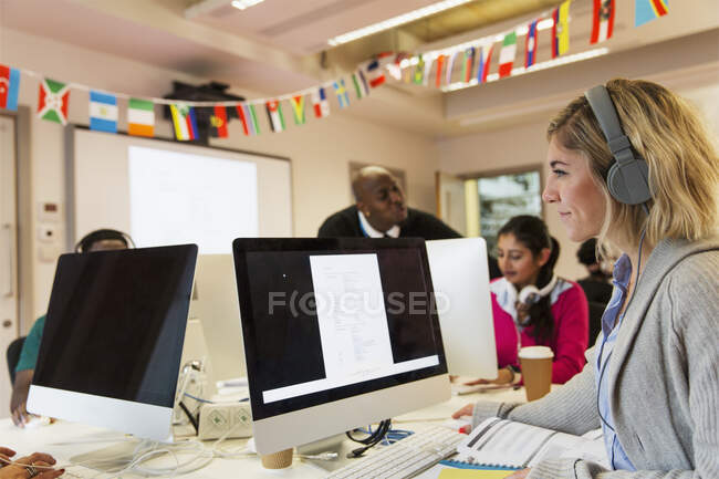 Female community college student with headphones using computer in computer lab classroom — Stock Photo