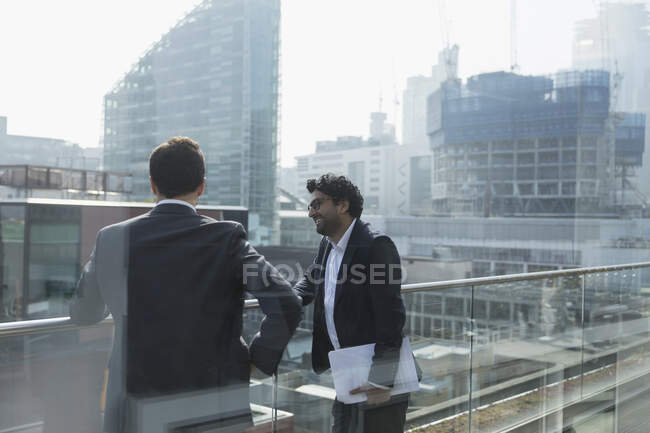 Empresarios hablando en soleado, balcón urbano, Shoreditch, Londres - foto de stock