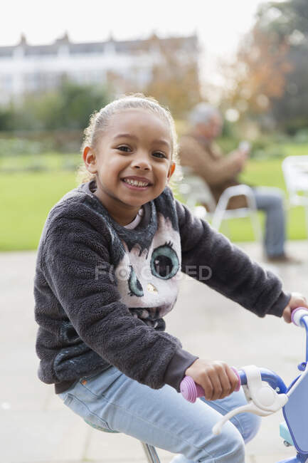 Портрет улыбающейся девушки, катающейся на велосипеде на детской площадке — стоковое фото